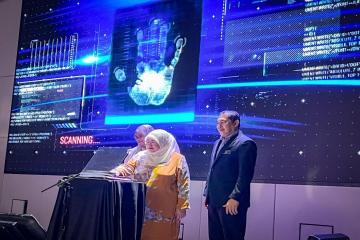 Seorang wanita dan lelaki sedang meletakkan tangan mereka di mesin pengecam 